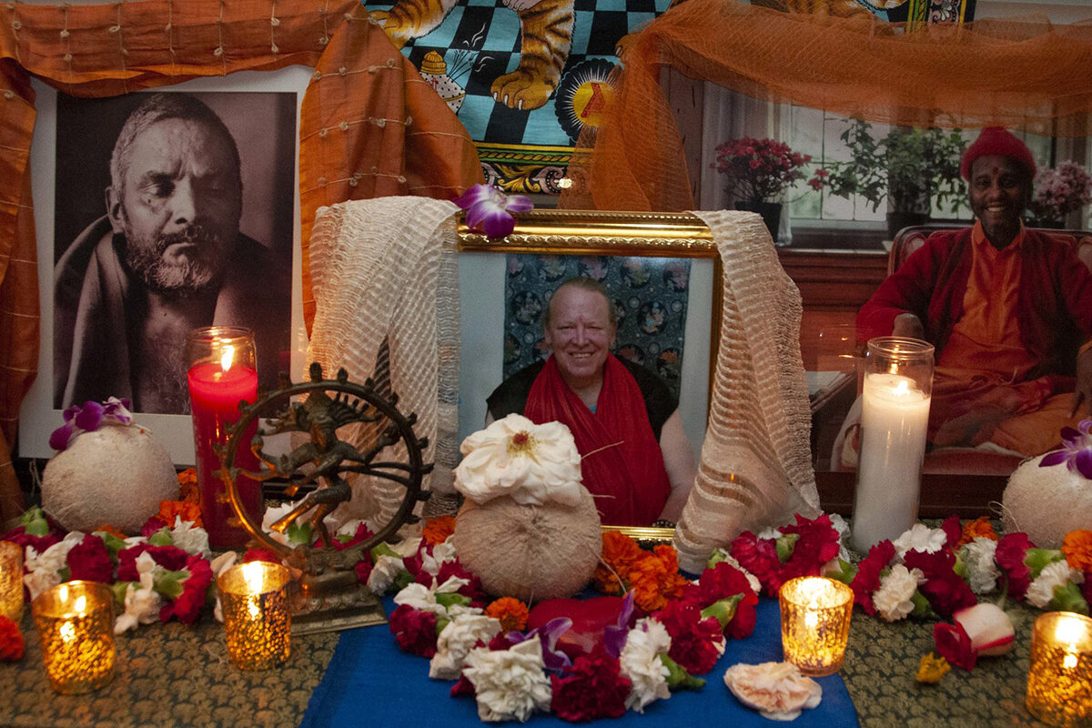 Tantric puja altar with photographs of lineage teachers, candles, and flowers.